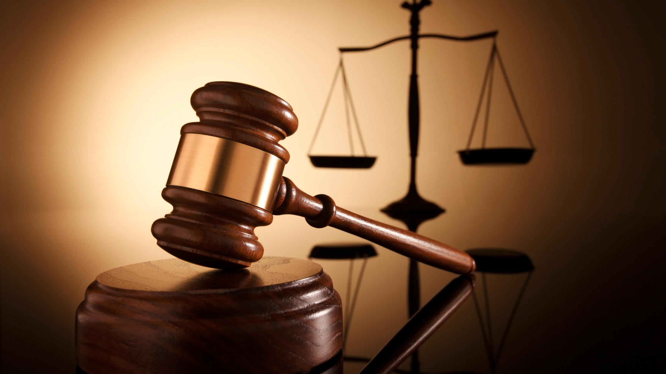 A wooden judge's gavel in front of the scales of justice