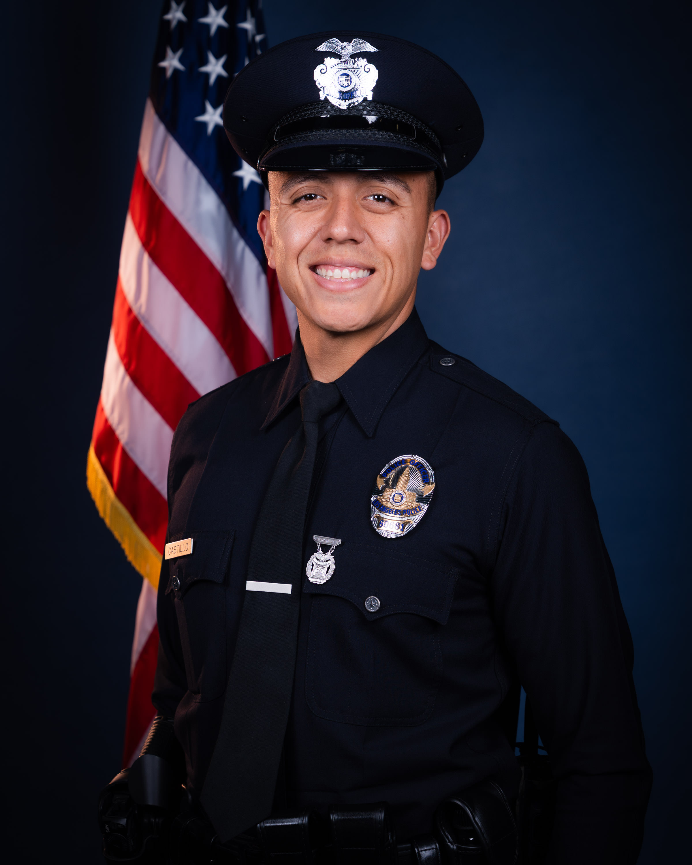 Officer Christopher Moses Castillo in LAPD uniform standing in front of an American flag